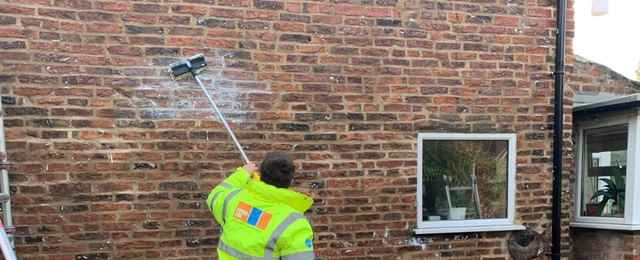 Damp patches caused by rainfall surveyor lady is cleaning the wall outside