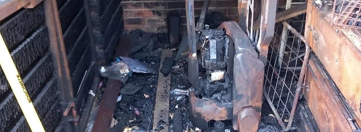 Fire-damaged supermarket loading area filled with charred debris and burnt equipment.