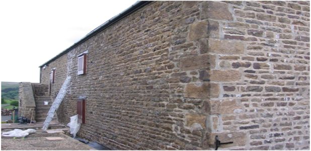 Applying masonry protection cream to a solid stone wall to prevent water penetration