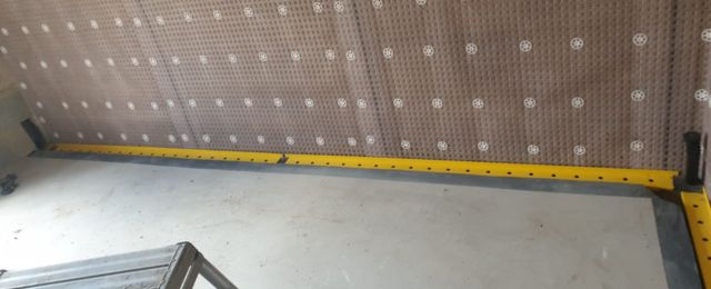 Interior construction scene with concrete floor and basement wall covered in damp-proofing waterproofing membrane