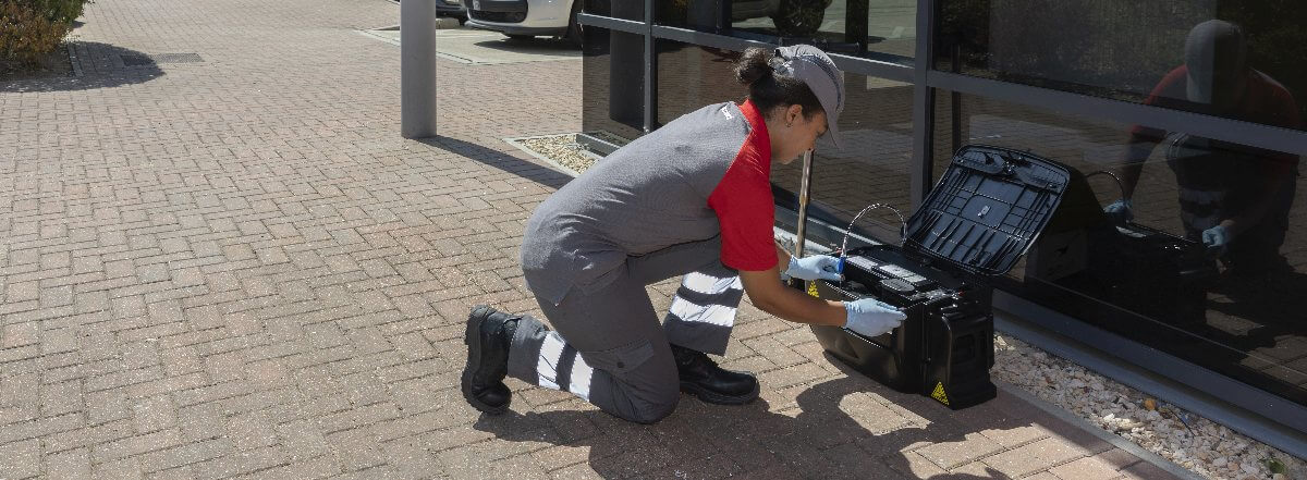Elimimair Connect multi-catch non-toxic rat trap being set up by female pest control technician outside of office building