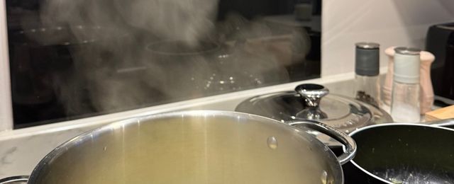 image of open pot on hob, releasing steam creating moisture in the home.